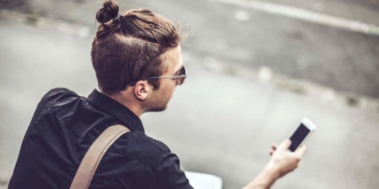 manbun styled man holding mobile