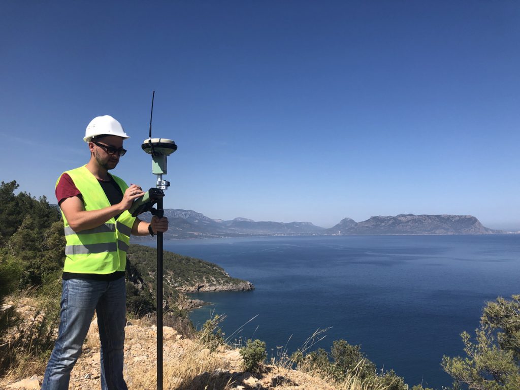 Geodetic engineer surveyor in white hard hat doing measurements with GNSS satellite receiver