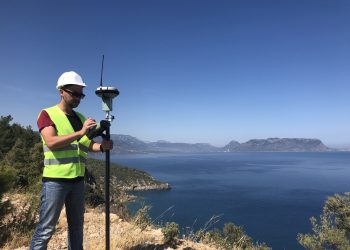 Geodetic engineer surveyor in white hard hat doing measurements with GNSS satellite receiver