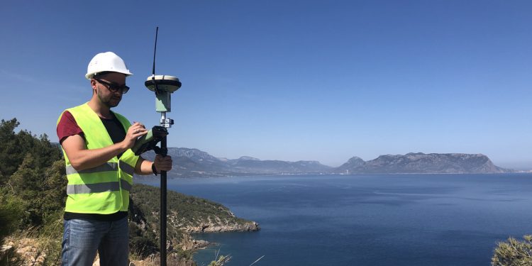 Geodetic engineer surveyor in white hard hat doing measurements with GNSS satellite receiver