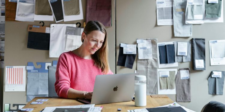 woman in red long sleeve shirt sitting in front of silver macbook